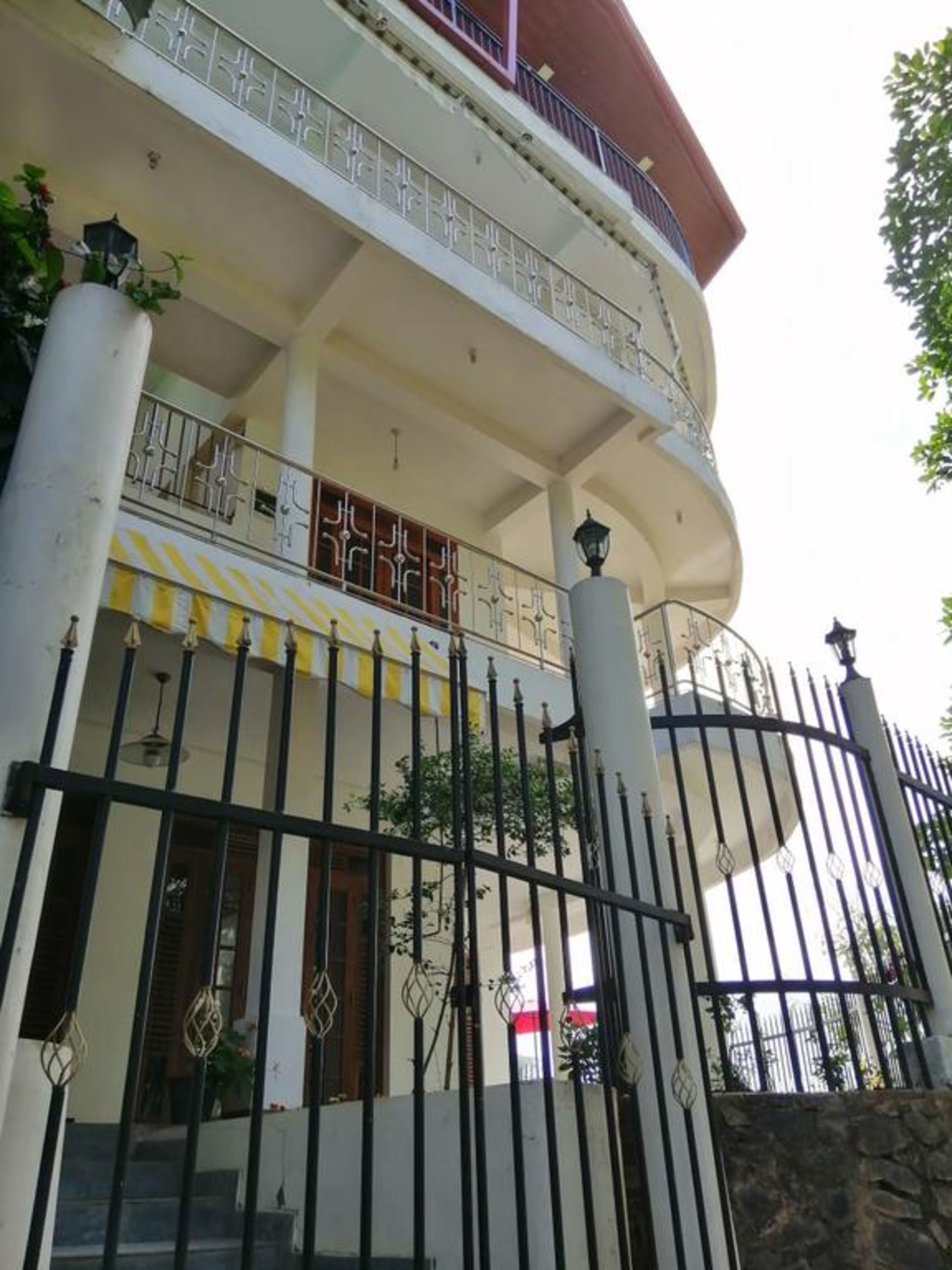 Un immeuble à plusieurs étages doté d’un balcon, d’une entrée sécurisée par un portail et d’un escalier menant à l’entrée.