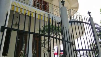 Un immeuble à plusieurs étages doté d’un balcon, d’une entrée sécurisée par un portail et d’un escalier menant à l’entrée.