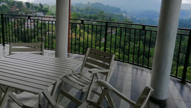 A balcony with a table and chairs, offering a view of a mountainous landscape. - Chef Guru Hotels (Bandarawela)