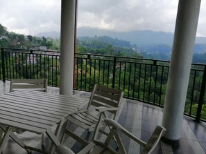 Un balcon doté d’une table et de chaises, offrant une vue sur un paysage montagneux.