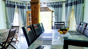 A dining area with a long table, chairs, and a fruit bowl. - Chef Guru Hotels (Bandarawela)