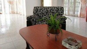 A living room with a sofa, a coffee table, and a TV mounted on the wall. - Chef Guru Hotels (Bandarawela)