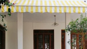 A building entrance with a set of blue stone steps leading up to a door, flanked by potted plants and a yellow and white striped awning. - Chef Guru Hotels (Bandarawela)
