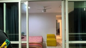 Una habitación con una cama, un ventilador de techo y un ventanal corredera que da a otra estancia.