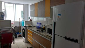 Una cocina con refrigerador, microondas, lavaplatos y armarios de madera.