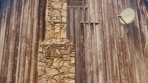 Ein rustikales Holzhaus mit Steinofen und Satellitenschüssel.