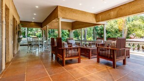 A covered outdoor seating area with wooden furniture and a tiled floor. - Christie's at 32 on Russell (Mbombela)