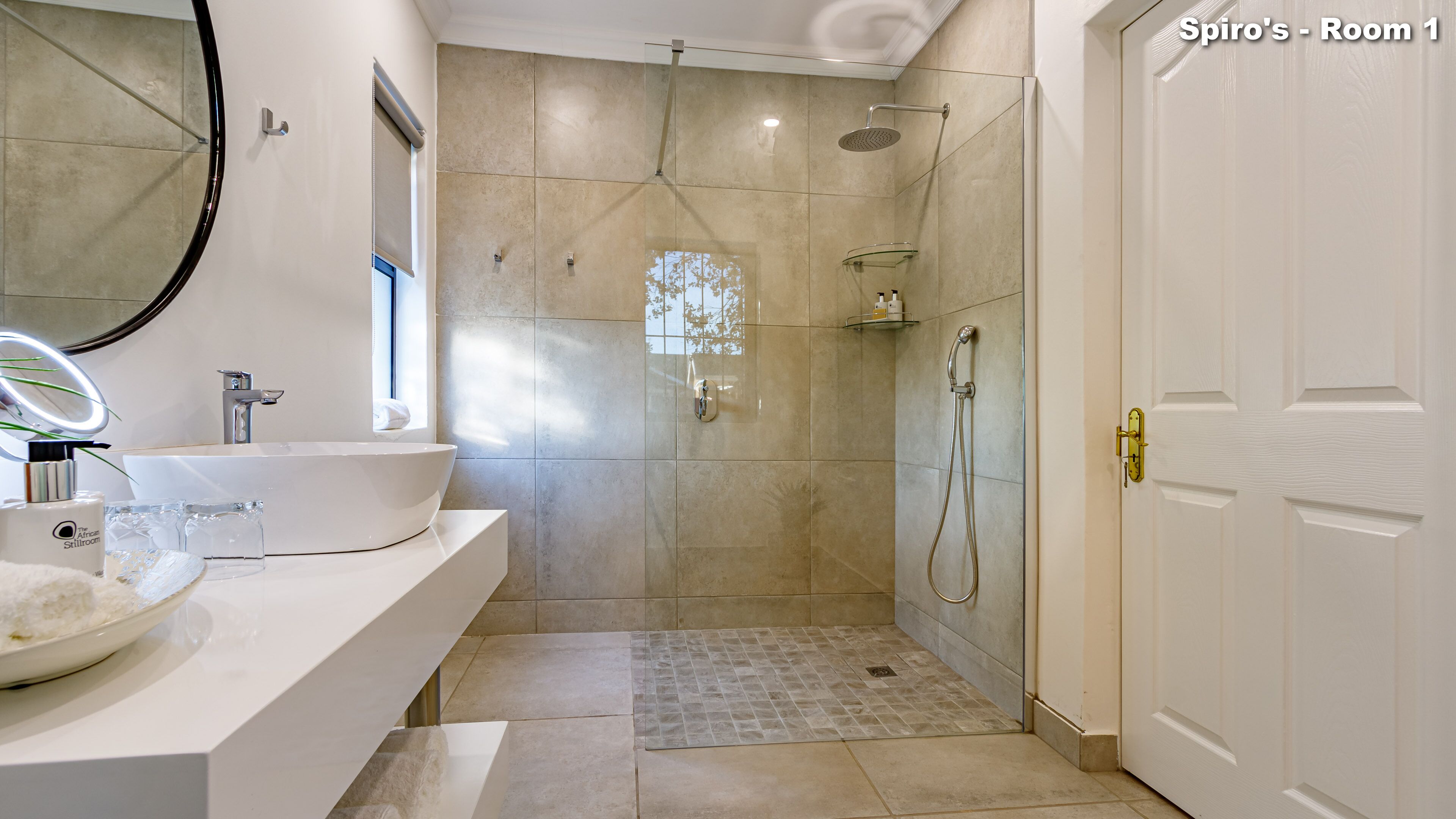 Un baño moderno con un lavamanos grande, espejo y zona de ducha.