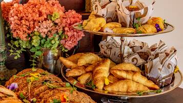 A buffet with various breads, pastries, and flowers.