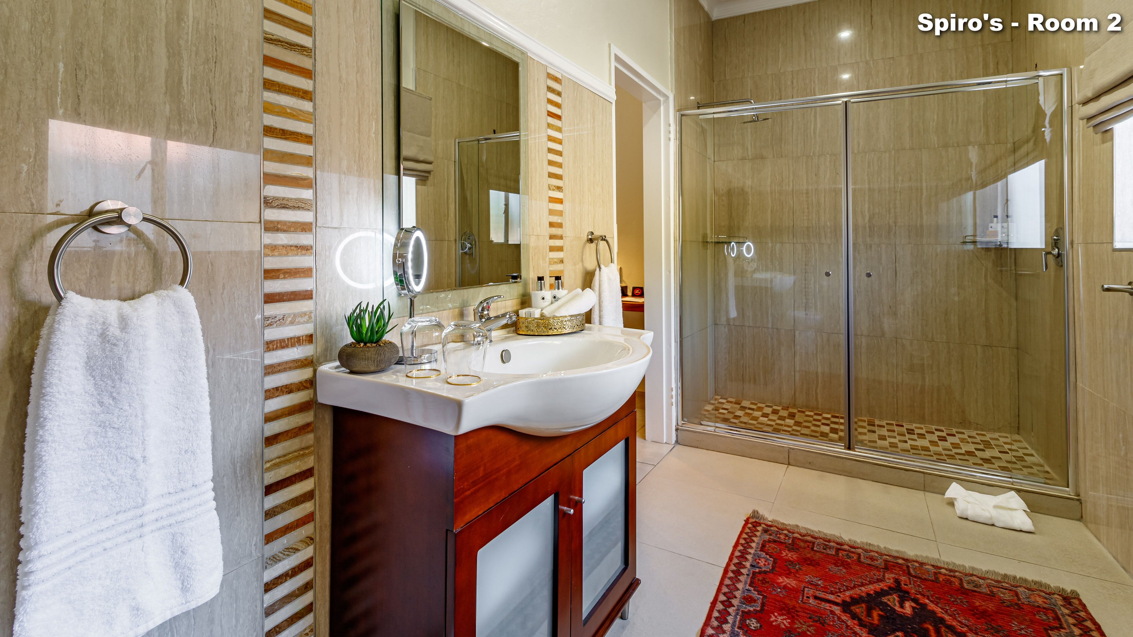 A modern bathroom with a large mirror, a white sink, and a glass-enclosed shower.