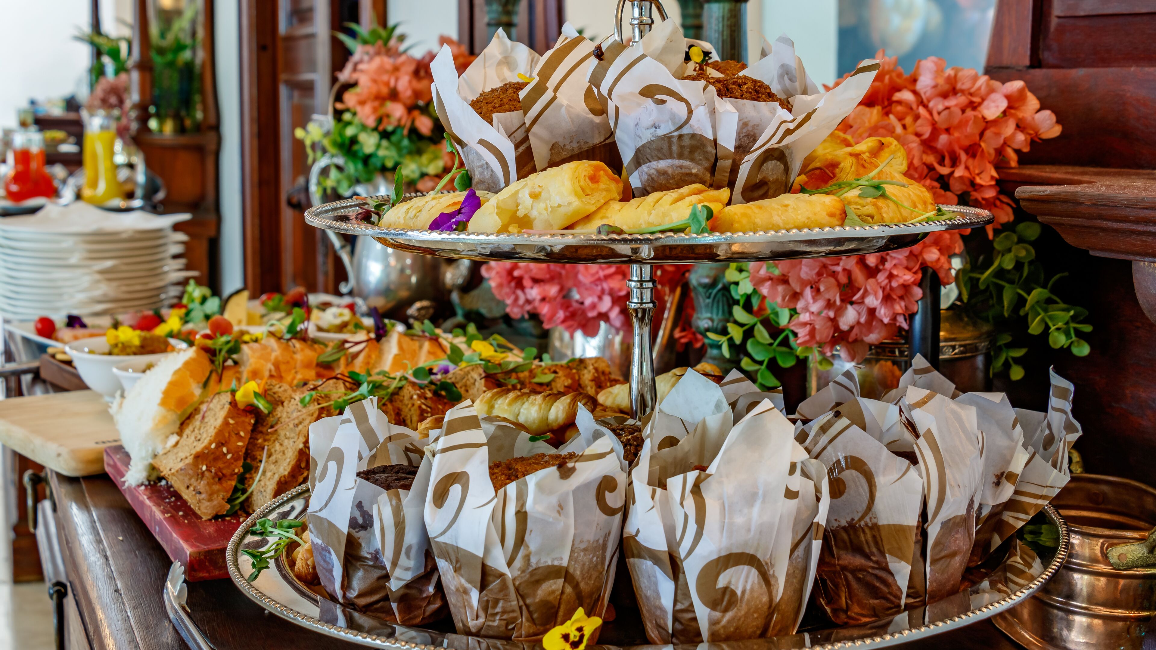 Un buffet proposant une variété de plats, notamment des pâtisseries et des sandwichs, disposés sur un plateau en argent.