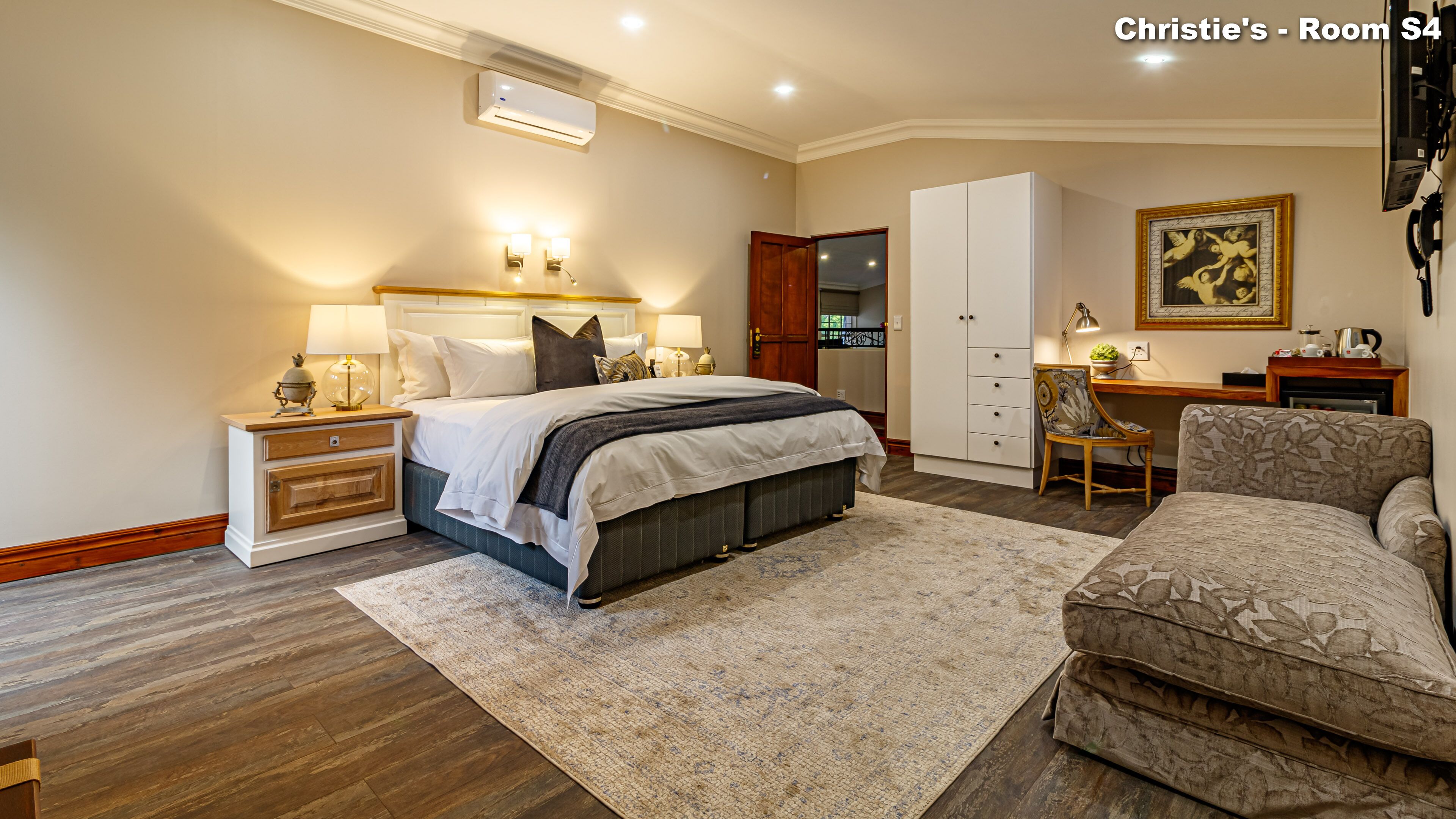 A bedroom with a bed, bedside tables, a wardrobe, a desk, and a chair.