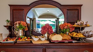 A buffet table with various food items and floral decorations. - Christie's at 32 on Russell (Mbombela)