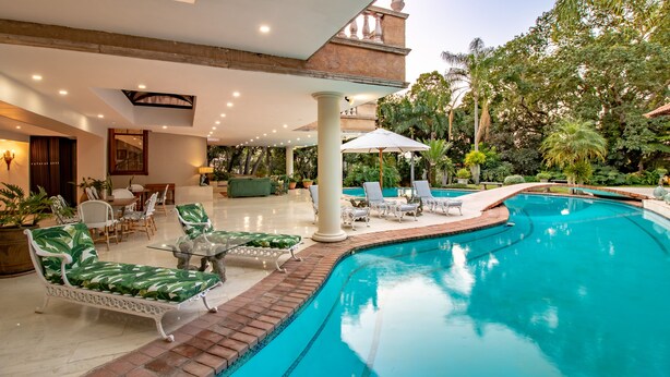 A pool area with lounge chairs and a dining area. - Christie's at 32 on Russell (Mbombela)