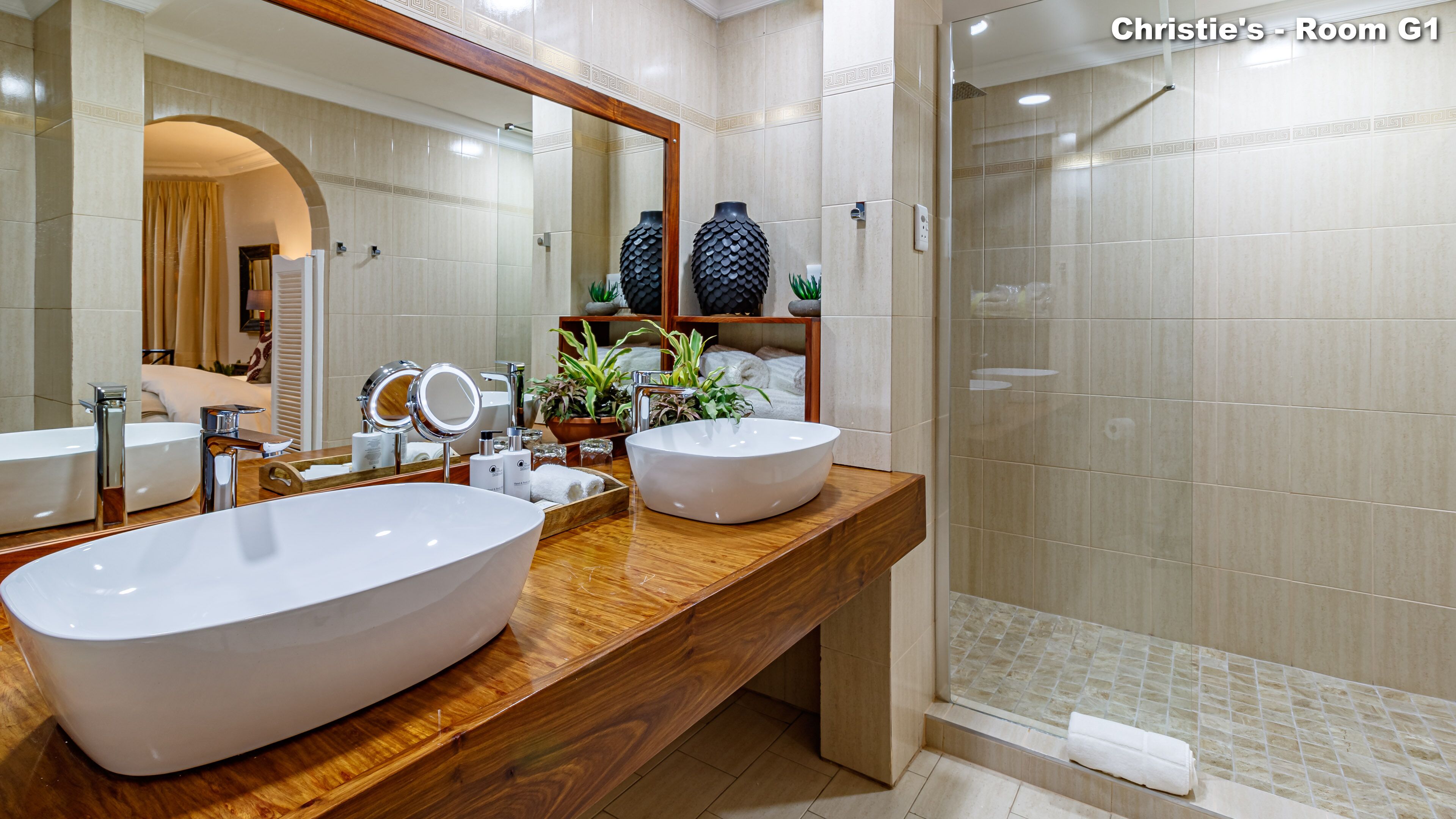 A bathroom with two large sinks, a mirror, and a shower area.