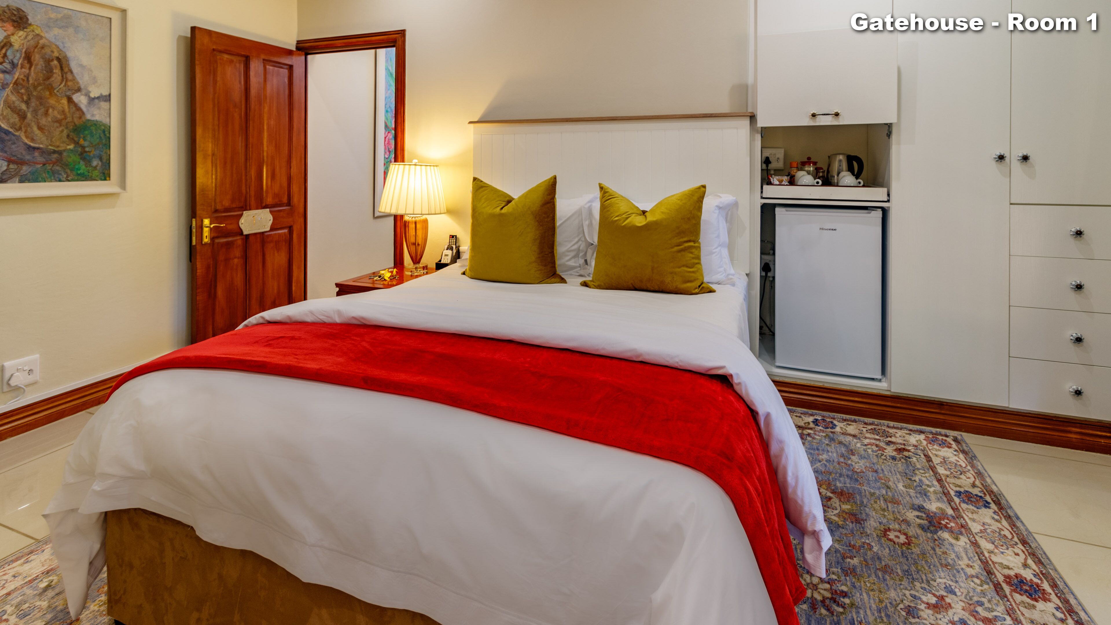 Une chambre d’hôtel équipée d’un lit, d’une table de chevet, d’une lampe et d’un petit réfrigérateur.