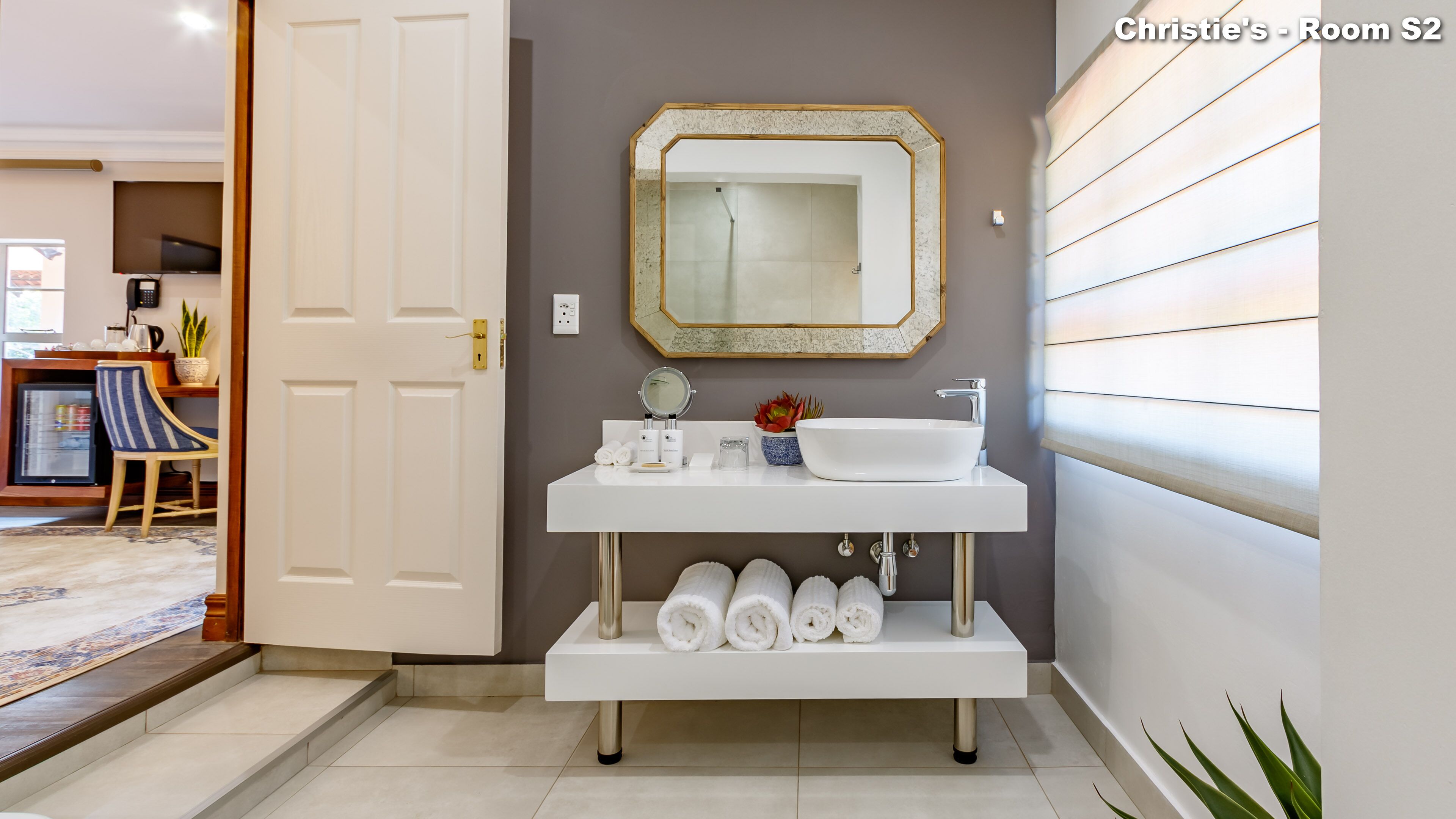 Une salle de bain moderne avec un meuble-lavabo blanc, un grand miroir et un évier. On y trouve des serviettes et des articles de toilette sur le meuble-lavabo.