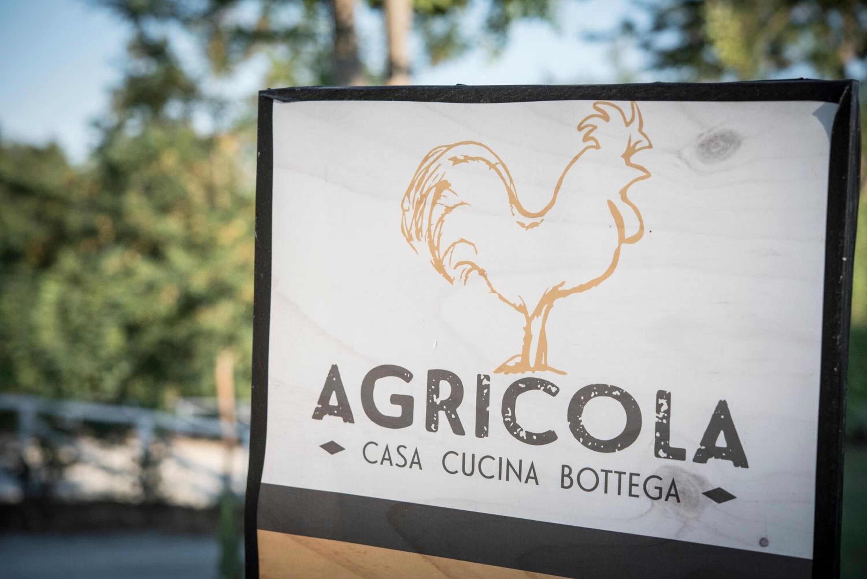Une enseigne représentant un coq, avec les mots « AGRICOLO » et « CASA CUCINA BOTTTEGA ».