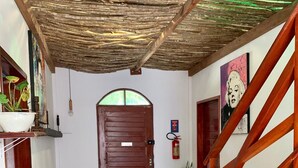 A spacious living area with a wooden staircase, a large wooden door, and various potted plants. - Residencial Bem Te Vi (Jijoca de Jericoacoara)