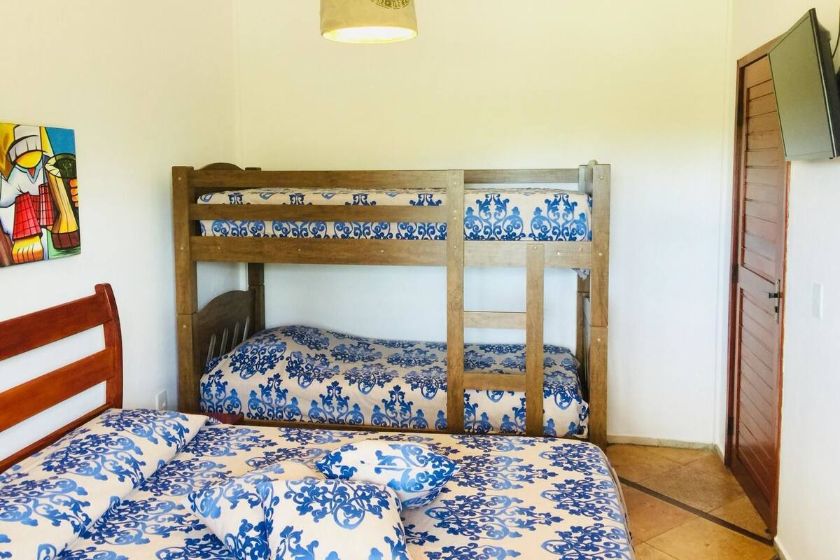 A bunk bed with blue patterned bedding, a wooden headboard, and a single bed with matching bedding.