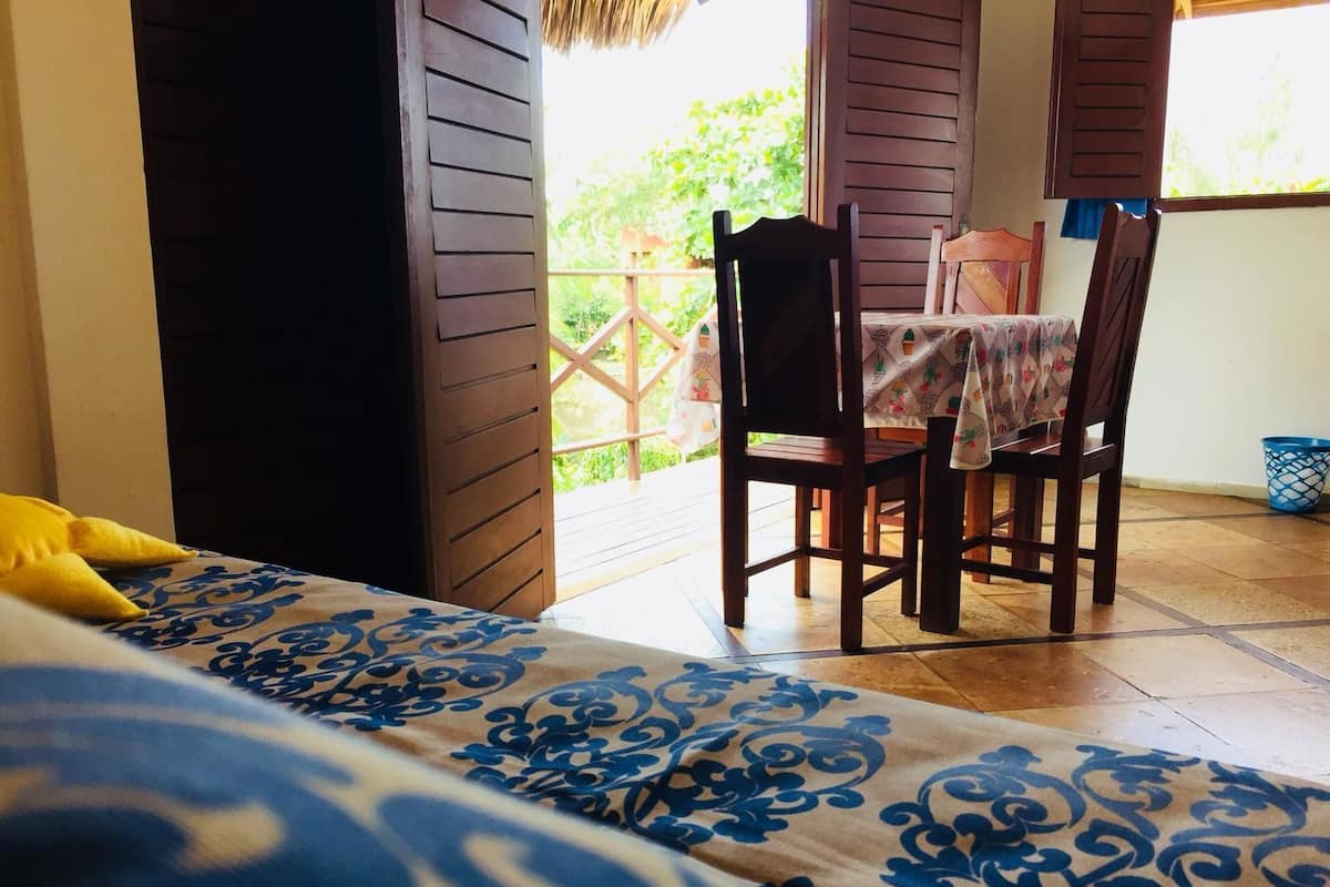 A room with a bed, a chair, and a table with a tablecloth.