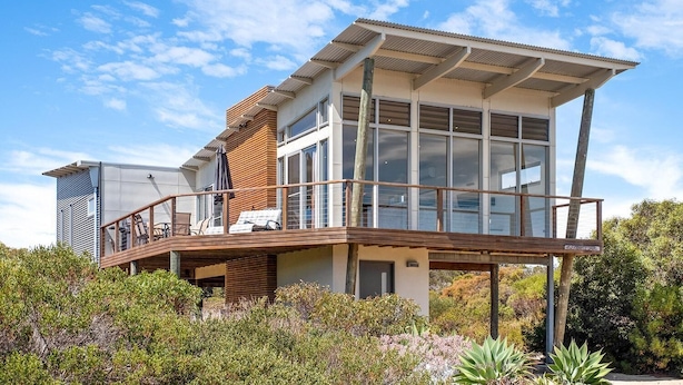 A modern two-story house with a balcony, large windows, and a view of the surrounding greenery. - Lakeview - A modern and beautifully designed holiday home (Marion Bay)