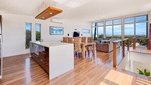A spacious living area with a kitchen, dining area, and large windows offering views of the outdoors. - Lakeview - A modern and beautifully designed holiday home (Marion Bay)
