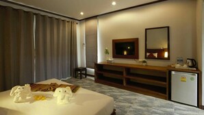 A hotel room with a bed, a desk, a mirror, a small refrigerator, and a window with curtains. - WELCOME TO KHAOLAK MOUNTAIN VIEW (Khuekkhak)