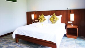 A hotel room with a wooden headboard, a large bed with white bedding, two bedside tables with lamps, and a tiled floor. - WELCOME TO KHAOLAK MOUNTAIN VIEW (Khuekkhak)