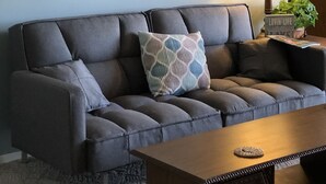 A living room with a grey sofa, a wooden coffee table, and a lamp.