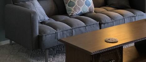 Un salon avec un canapé gris, une table basse en bois et une lampe.