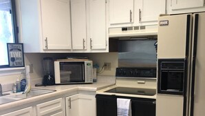 A kitchen with white cabinets, a microwave, an oven, and a refrigerator.