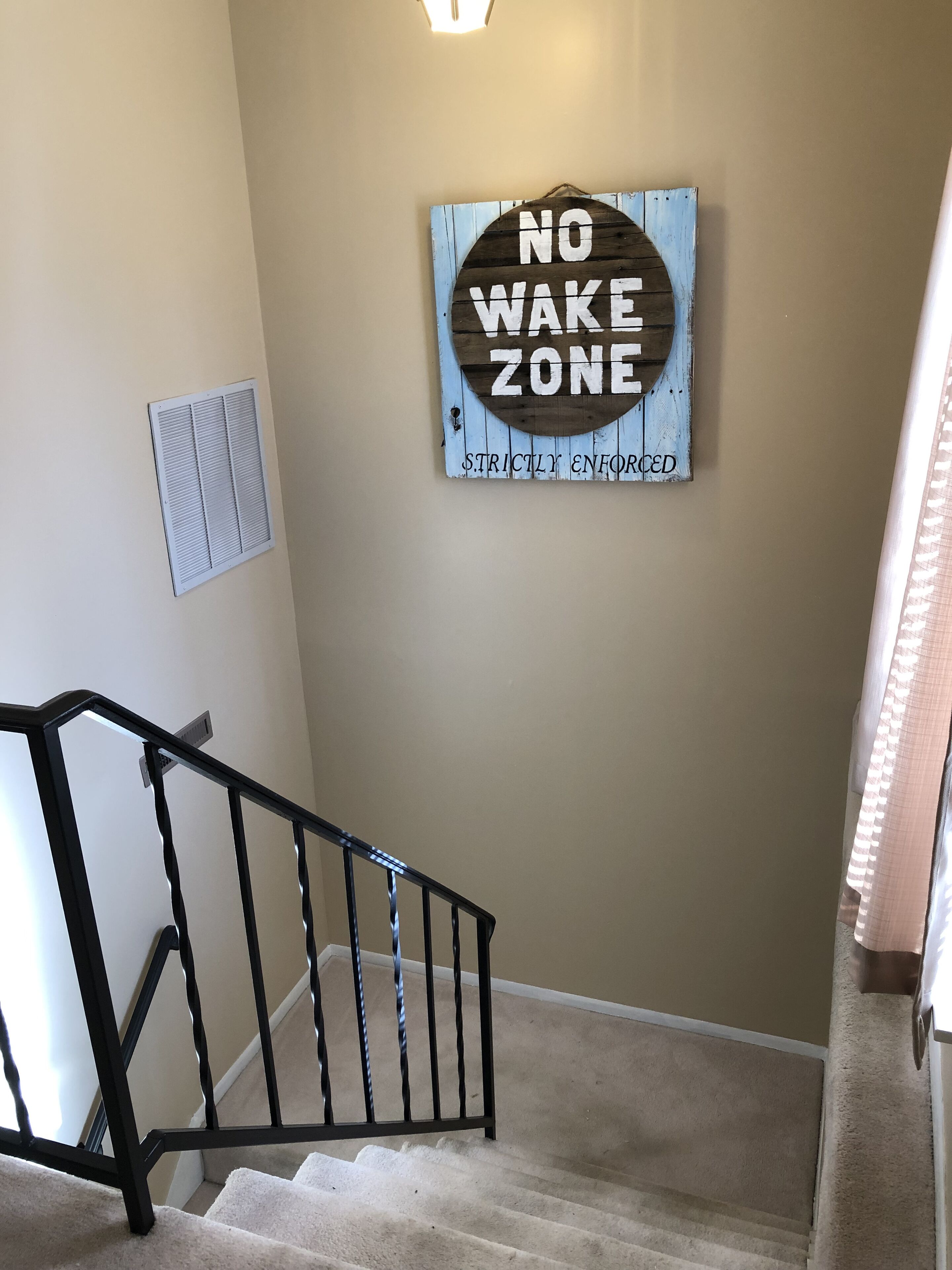 A staircase with a 'No Wake Zone' sign on the wall.