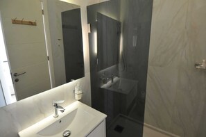 A modern bathroom with a white sink, a mirror, and a glass-enclosed shower. - Batroun Bahsa Bay (Batroun)