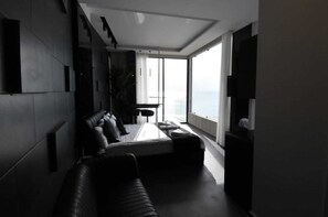 Une chambre d’hôtel moderne dotée d’un grand lit, d’un canapé, d’un bureau et d’une grande fenêtre donnant sur la ville.