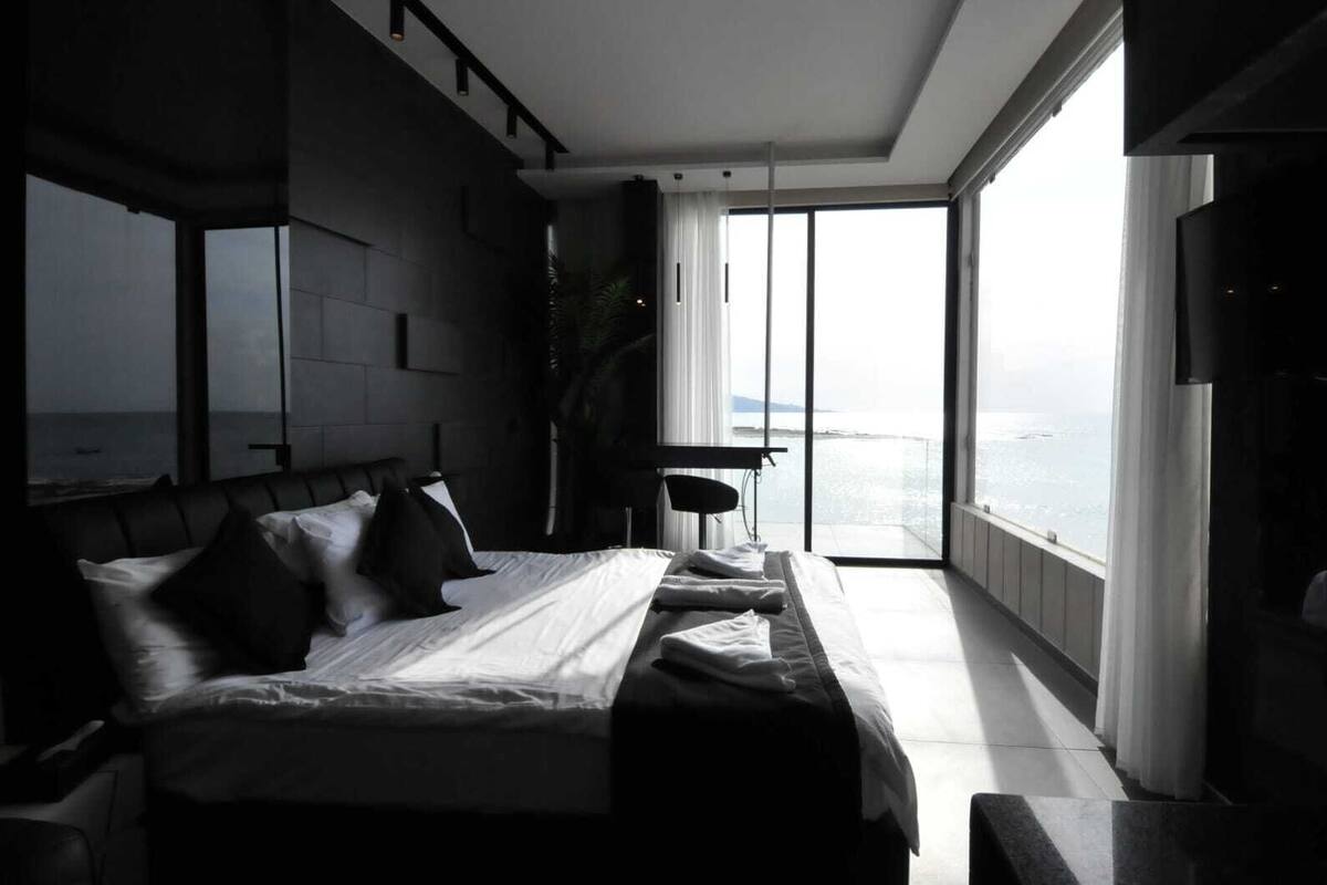 Une chambre moderne avec un grand lit, un bureau et une vue sur la mer.