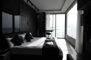 Une chambre moderne avec un grand lit, un bureau et une vue sur la mer.