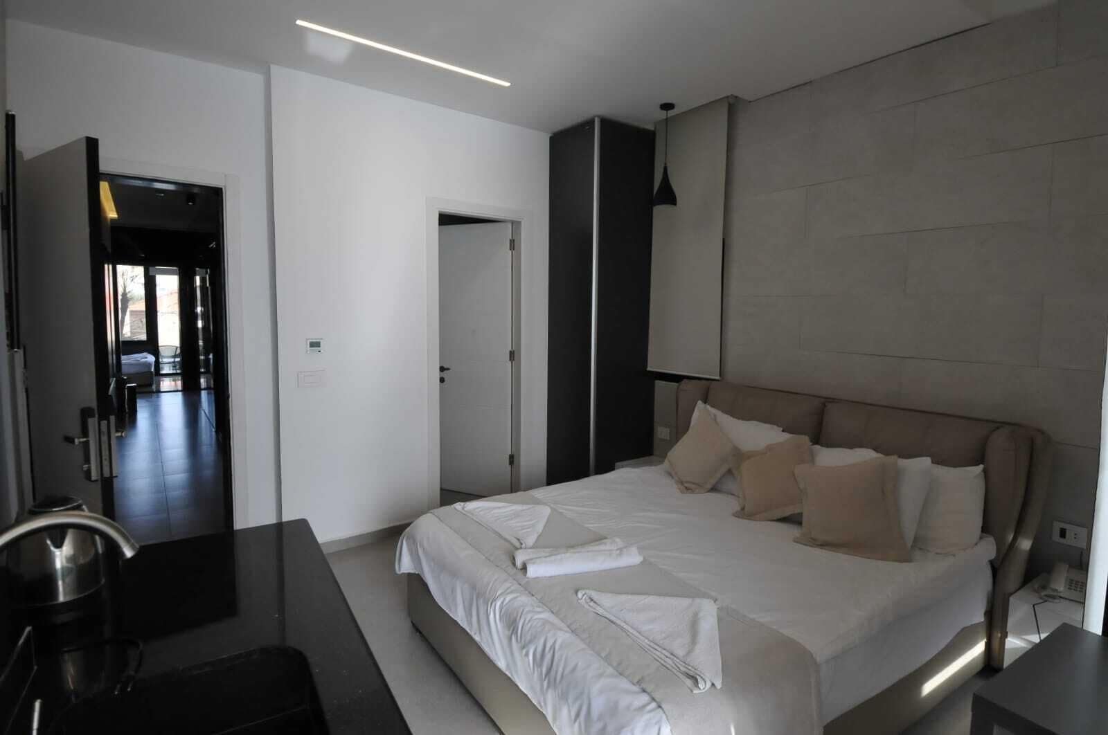 A modern hotel room with a large bed, a desk, and a separate bathroom area.