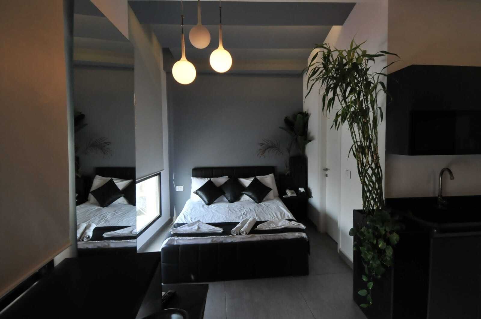 Un dormitorio moderno con dos camas, un ventanal grande, un lavabo y una planta en maceta.