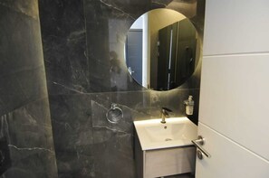 Une salle de bain avec un mur en marbre, un lavabo avec un miroir et une porte.
