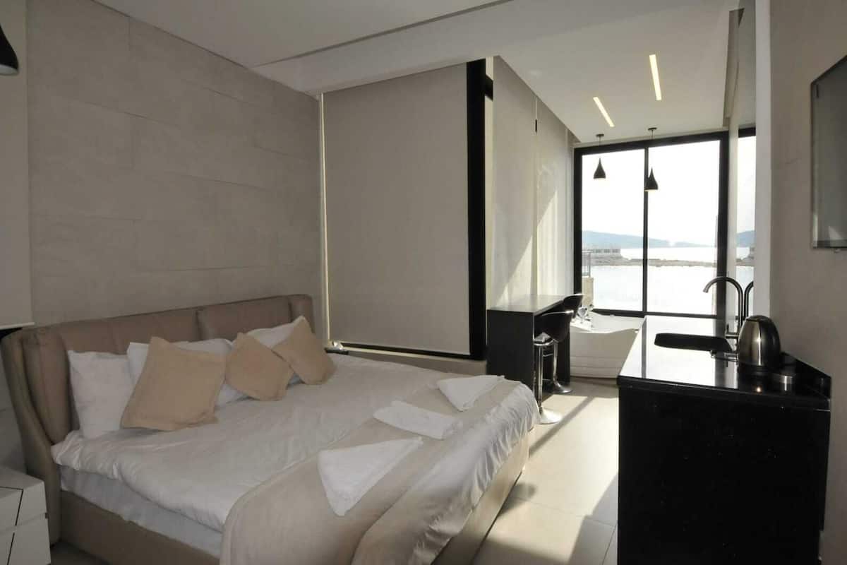 Une chambre d’hôtel moderne avec un grand lit, un bureau et une vue sur la mer.