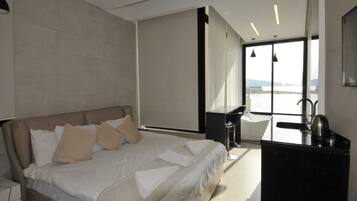 Habitación de hotel moderna con una cama grande, un escritorio y vistas al mar.