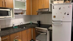 Una cocina con armarios de madera, microondas, estufa y refrigerador.