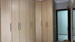 Una habitación con un armario grande, una puerta que da a un balcón y una pequeña mesa.
