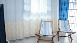 Dos sillas de madera con tela a rayas, una puerta azul y una cortina con estampado de hojas amarillas.