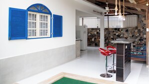 Una cocina con pared de piedra, un refrigerador y una barra con taburetes.