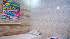 Una habitación con dos camas, una pared de madera y un cuadro de colores.