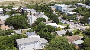 Un área residencial costera con casas, una playa y una vista despejada del océano.