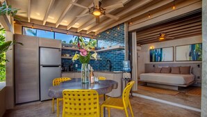 A modern kitchen with a dining area, featuring a stainless steel refrigerator, a blue tiled backsplash, and a dining table with yellow chairs. - Entire Palmar · Stunning 4 BR Oceanfront Townhome, amazing views. (Sayulita)