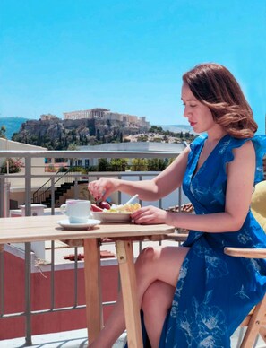 A woman dining at a table with a view of ancient ruins in the background. - Happy place at the foot of Acropolis. (Athens)
